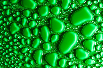 Droplets of water on a green, matte background illuminated with a delicate light.