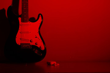 electric guitar in front of red colro wall with headphones bluetooth