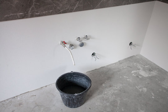 Construction bucket with dried mortar sluge on the concrete floor. Close up. Concept of repair and construction process. Finishing work at home. Rennovation and new interior.