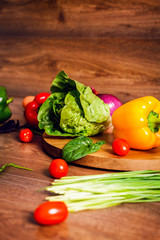 Red, yellow pepper and other vegetables on a brown wooden background.