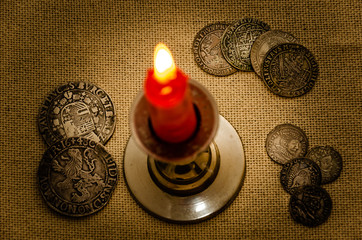 ancient silver coins and burning candle 