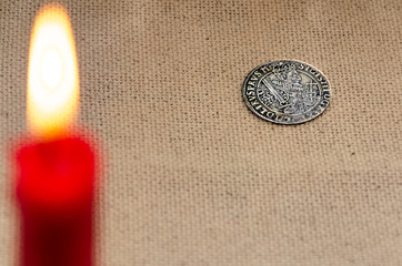 ancient silver coin and burning candle 