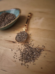 Healthy Chia seeds in a gold spoon on the wooden table close-up
