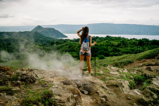 filipina girl looking at taal volcano crater lake from trail along rim near manila in the philippines