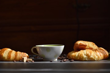 Coffee composition. Cup of coffee, croissants, sugar slices on a dark background 