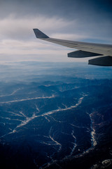 An aerial view of Chinese mountains from the airplane flying high above the ground. A look from the plane window.