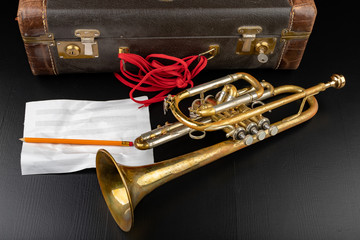 Old covered patina trumpet in a case. A historic wind musical instrument and a suitcase.