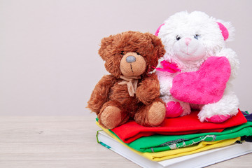 Donation concept. Donate box with kids clothes, books, school supplies and toys. Teddy bear with big pink heart in hands. Copyspace for text.