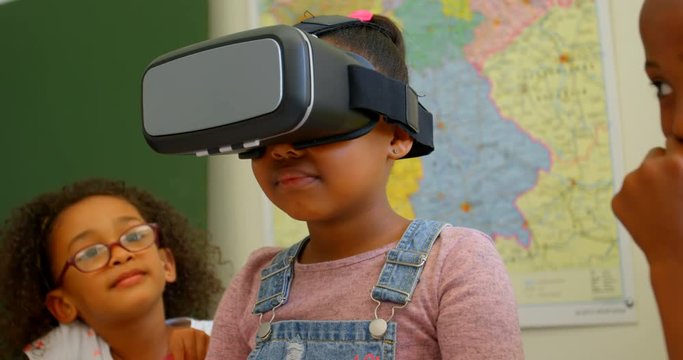 African American schoolgirl using virtual reality headset in classroom at school 4k