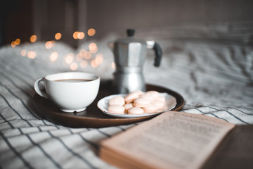 Cup of freah coffee with open book in bed. Good morning.