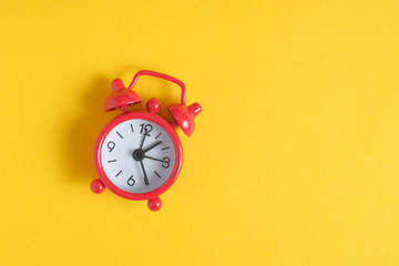 The concept of time management. Place for text. Red vintage clock on a yellow background on the left side.