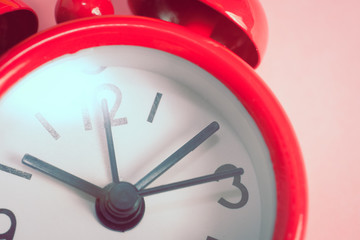 Red clock on a pink background with a flare.