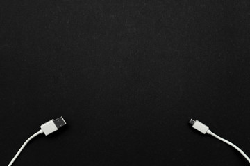 White USB cable in the lower left corner and micro USB cable in the lower right corner on a black background