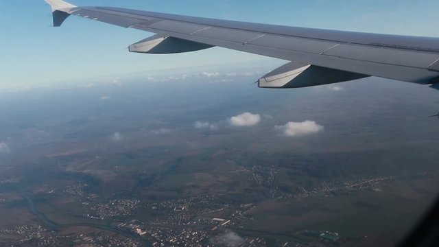 Stunning footage of aerial view above clouds from airplane window with blue sky. view of the earth from the sky through the clouds. 4K video. Aerial footage. Travel concept