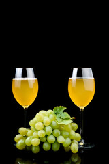 Glass of wine and grape on black background