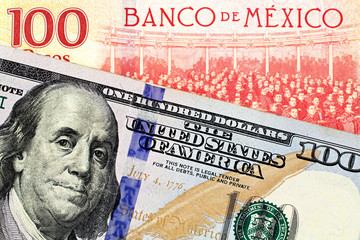 A close up image of a new American one hundred dollar bill with a Mexican one hundred peso bank note in macro