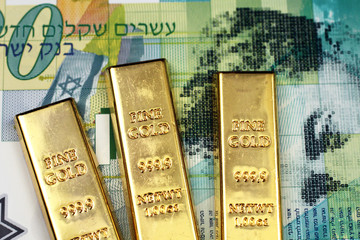 A close up image of a green twenty Israeli shekel bank note with three small gold bars in macro