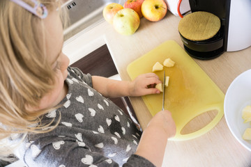 Little girl cutting apples for preparion smoothie