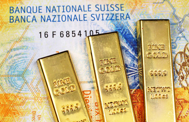 A close up image of a ten Swiss Franc bank note with three small gold bars in macro