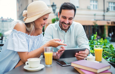 Young couple sitting in the cafe and having fun with tablet. Dating, relationships, love, romance, lifestyle, technology