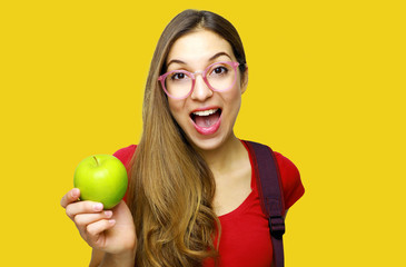 Fototapeta na wymiar Beautiful young woman over yellow background showing green apple very happy and excited, winner expression celebrating victory screaming with big smile