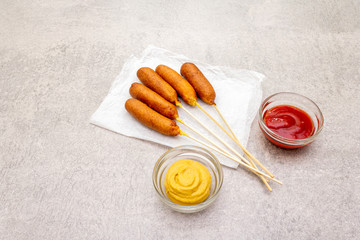 Corn dogs homemade with popular sauces. Traditional American street food. On stone background