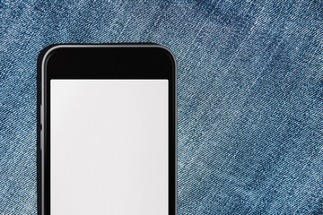 Mobile phone with blank mockup screen in the pocket of blue jeans with headphones