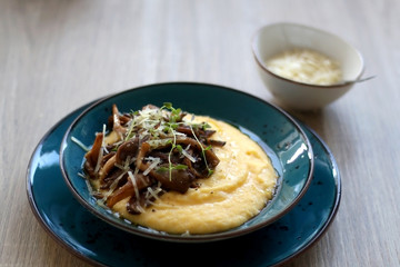 Fried mushrooms and polenta with cheese and herbs. Selective focus.