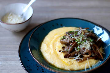 Fried mushrooms and polenta with cheese and herbs. Selective focus.