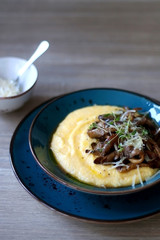 Fried mushrooms and polenta with cheese and herbs. Selective focus.