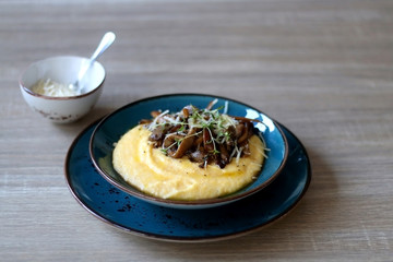 Fried mushrooms and polenta with cheese and herbs. Selective focus.