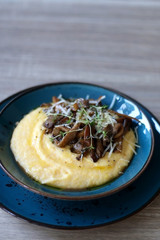 Fried mushrooms and polenta with cheese and herbs. Selective focus.