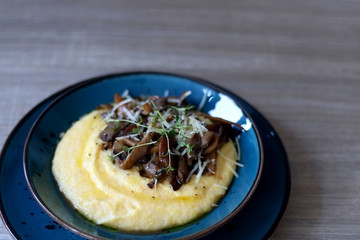 Fried mushrooms and polenta with cheese and herbs. Selective focus.