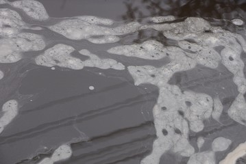 texture of dirty water and gray foam in the pond