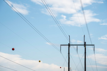 Fototapeta premium Electric poles with wires and cables set on a bright blue daylight sky.
