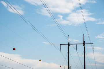 Electric poles with wires and cables set on a bright blue daylight sky.