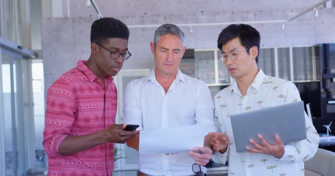 Multi-ethnic businessmen discussing over document in modern office 4k