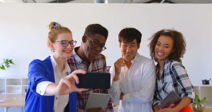 Young multi-ethnic business colleagues taking selfie with mobile phone in modern office 4k