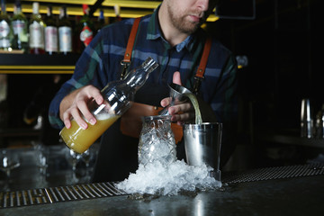 Barman making tropical cocktail at counter in pub, closeup