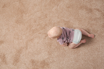 Fototapeta na wymiar Cute little baby crawling on carpet indoors, top view with space for text