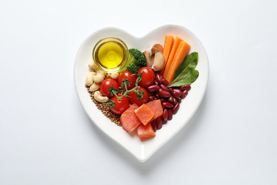 Plate with products for heart-healthy diet on white background, top view