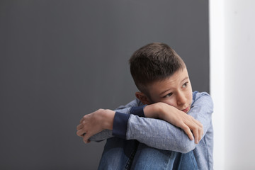Upset preteen boy sitting indoors. Space for text
