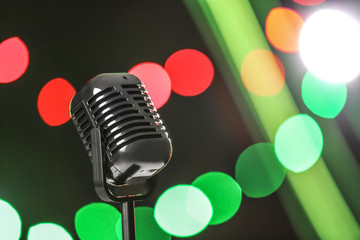 Fototapeta na wymiar Retro microphone against festive lights, space for text. Musical equipment