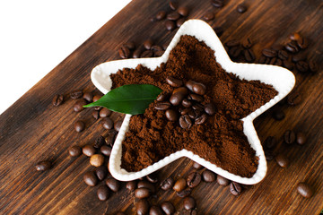 Ground coffee in a white bowl on a wooden board.