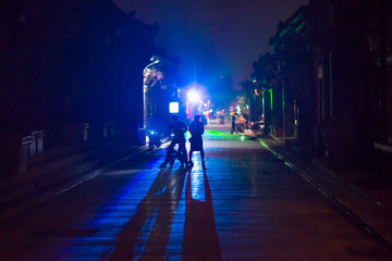 Pingyao, China - 08 13 2016: Silhouette and shadow of people in the alley in the night in city center. Lights in Pingyao at night. Pingyao, Shanxi, China