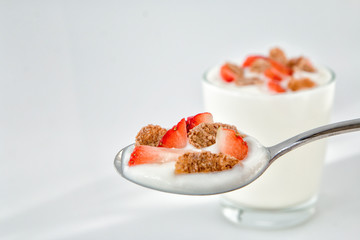 Natural yogurt in a spoon with strawberry and multigrain flakes. Top view