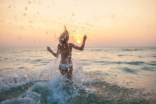 Woman running into the sea with lots of splashes