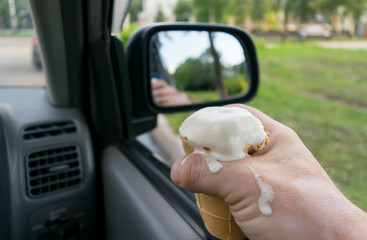 the driver holds the ice cream while driving a car