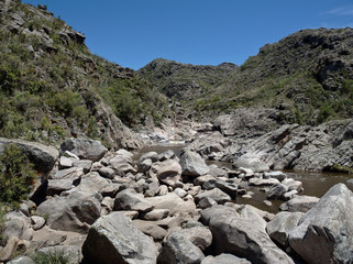 Fototapeta na wymiar View of the Yuspe river running through the mountains at Cerro Blanco reserve, near Tanti and Los Gigantes, Cordoba, Argentina