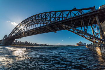 Sydney Harbour with sun shining through Sydney Harbour Bridge frame